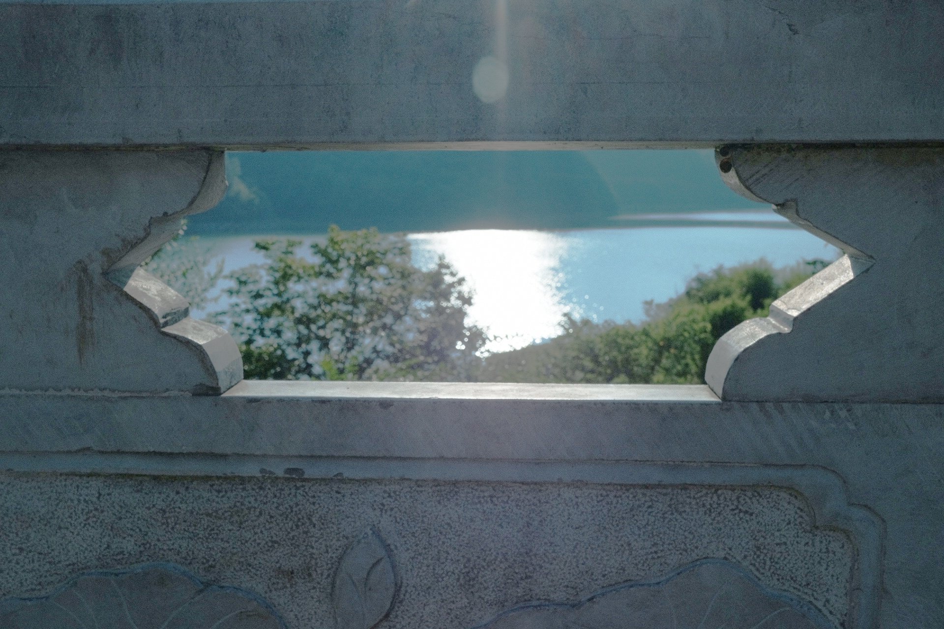 A stone window frame around distant trees and water