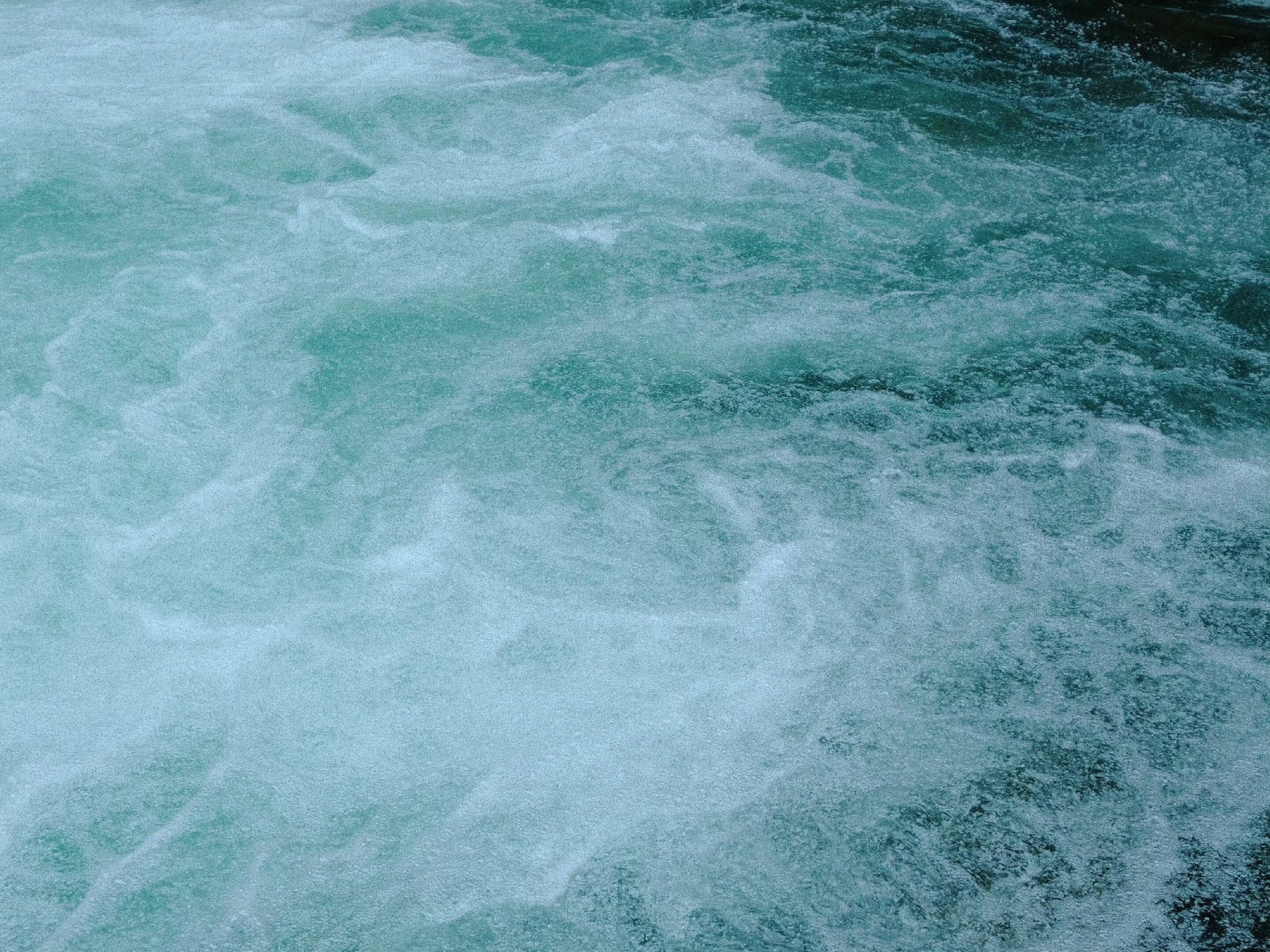 Rushing water churning into pale green