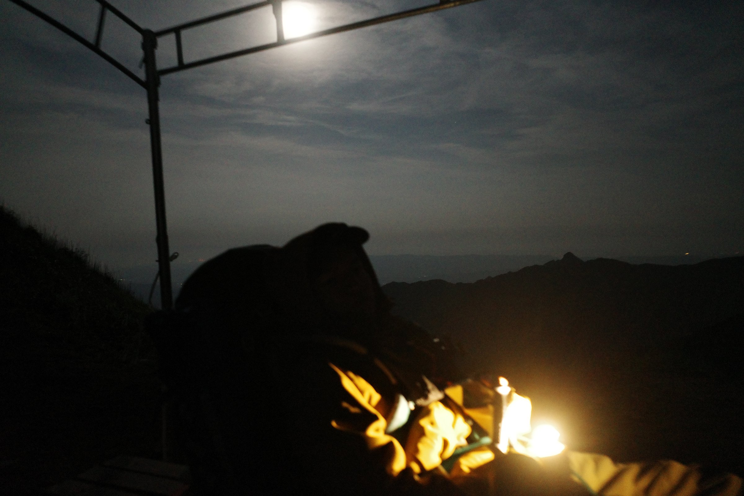 A small campfire at night, firelight on a profile
